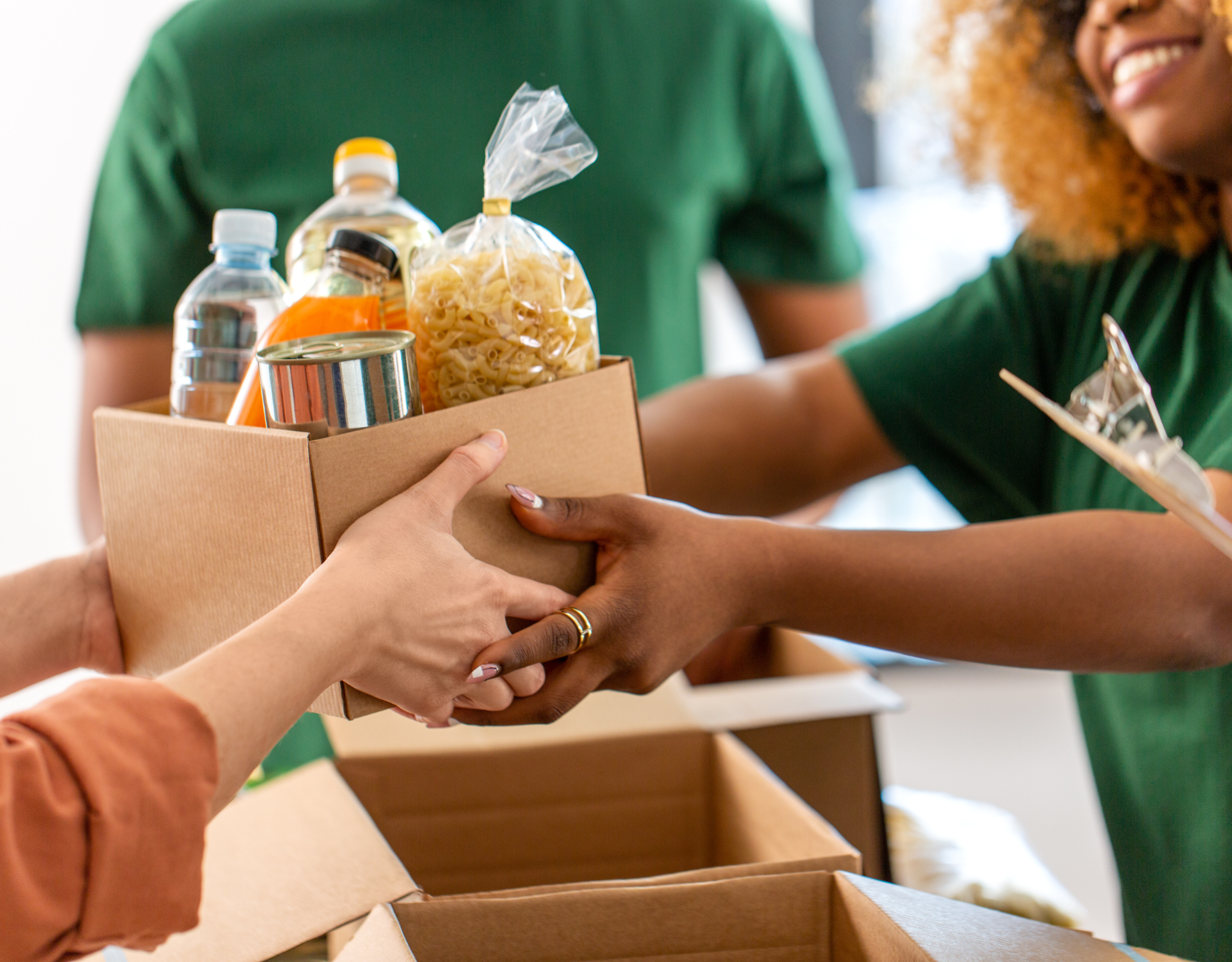 Volunteers exchanging a donation box with groceries representing community impact and corporate responsibility.