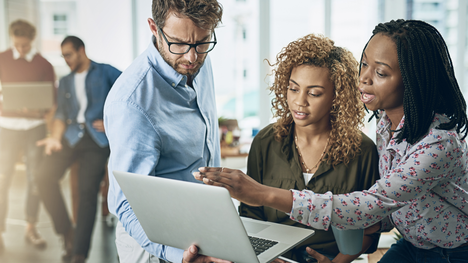 Team collaborating around a laptop representing workforce adoption of new technologies.