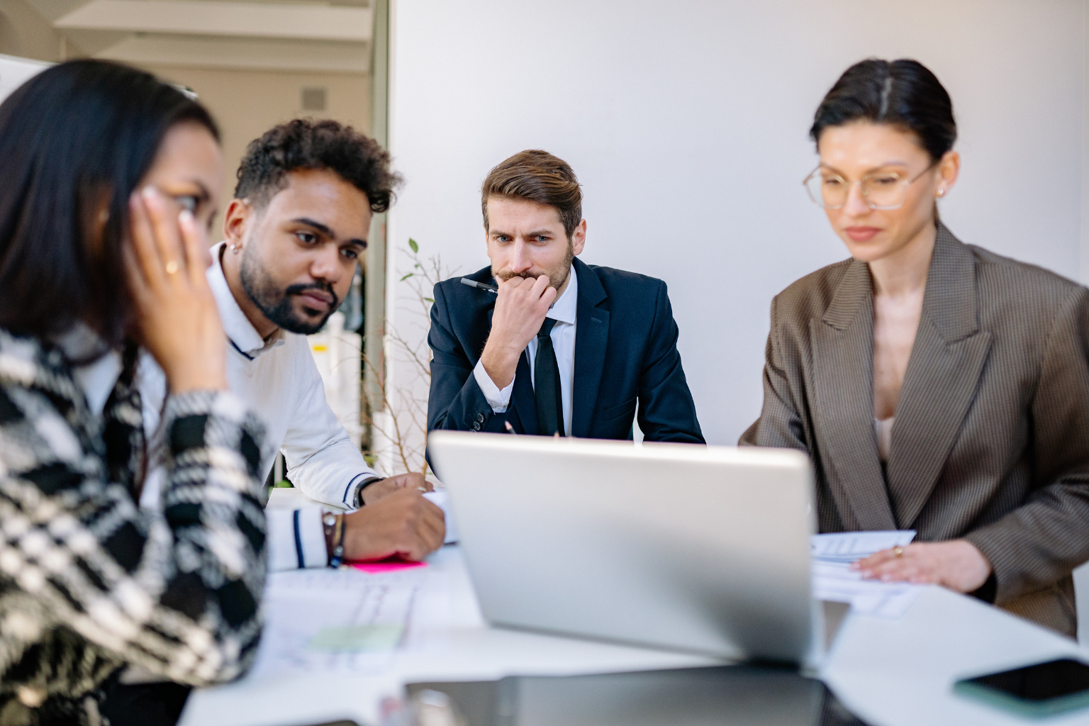 diverse group of professional men and women in deep thought over a laptop monitor