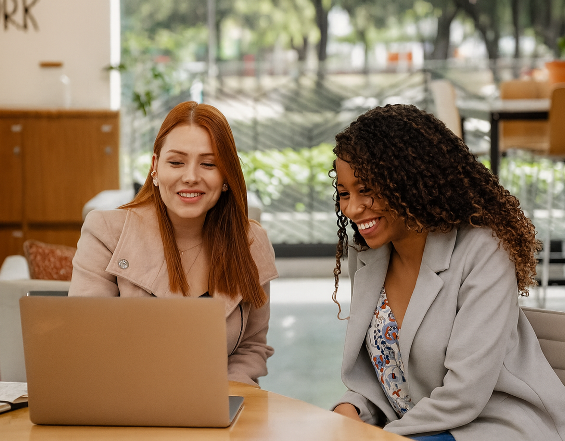 two young women smiling at a laptop