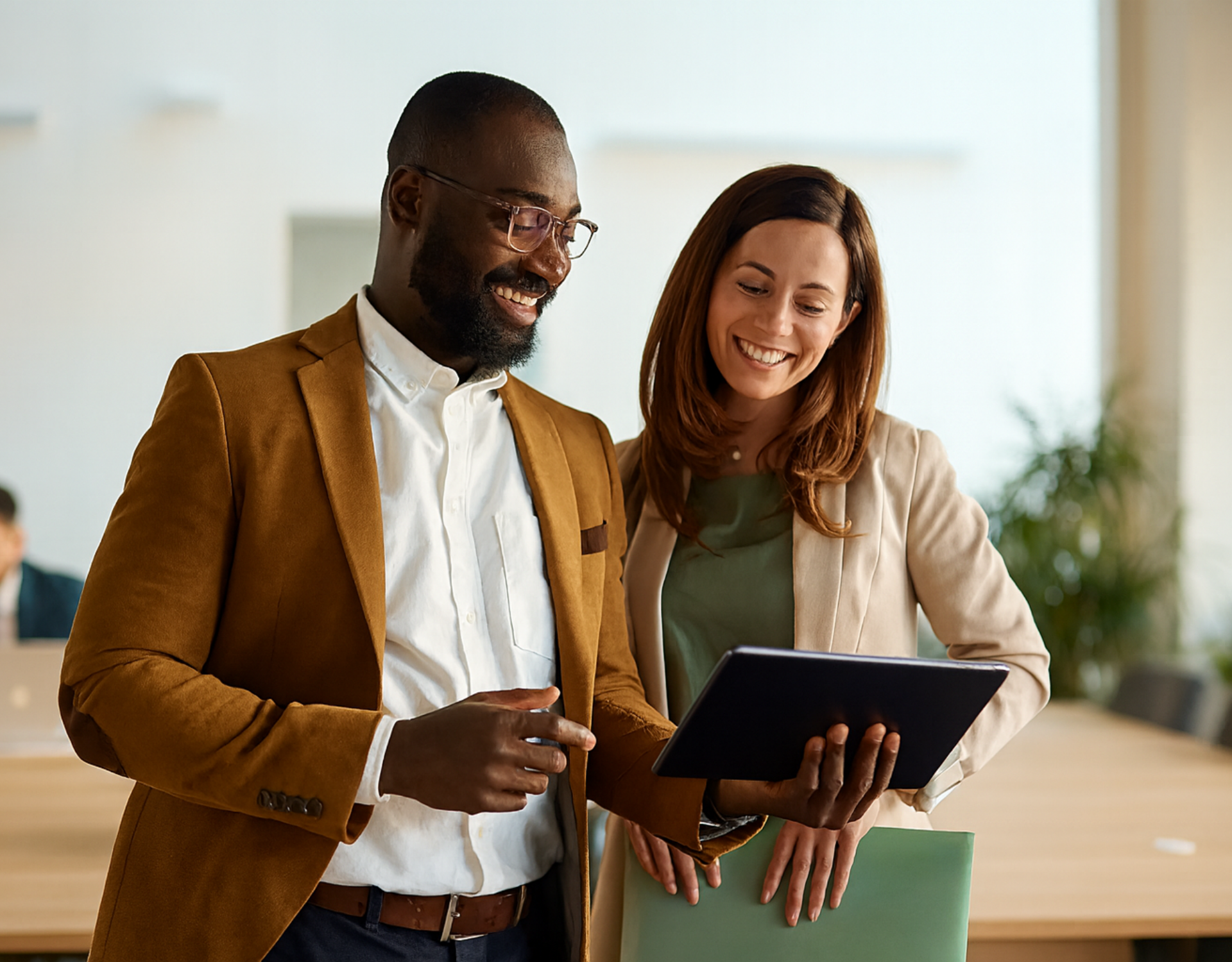 black male and white female pointing and smiling at a tablet