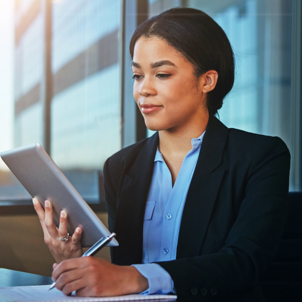 young black female looking at a tablet and taking notes