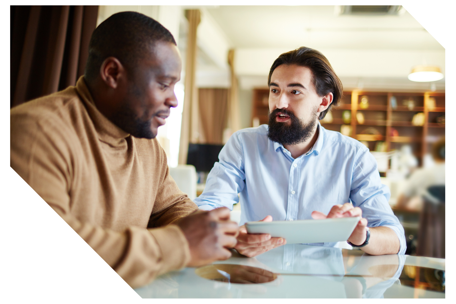 Two professionals discussing ideas while reviewing a tablet during a collaborative meeting.