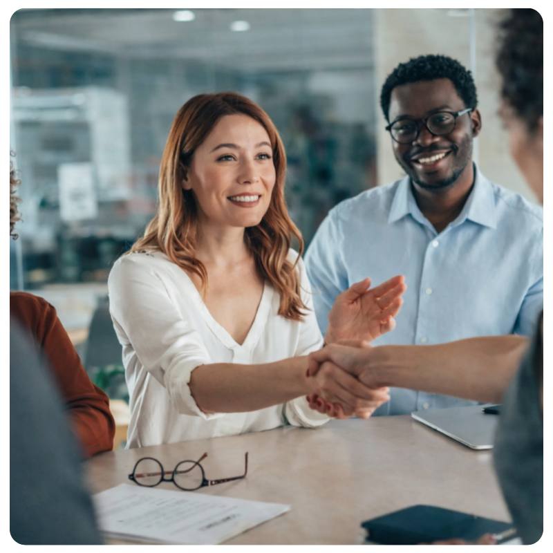Professionals shaking hands across a meeting table to celebrate a successful partnership.